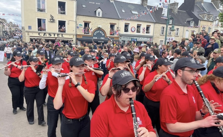 A photo of Jordan Chambill and over 50 other band members walking in a parade with instruments.
