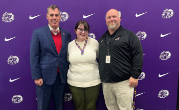 Holly Miller poses for a photo in front of a North logo backdrop with Superintendent Mark Garrett and Principal Dr. John Shepard.